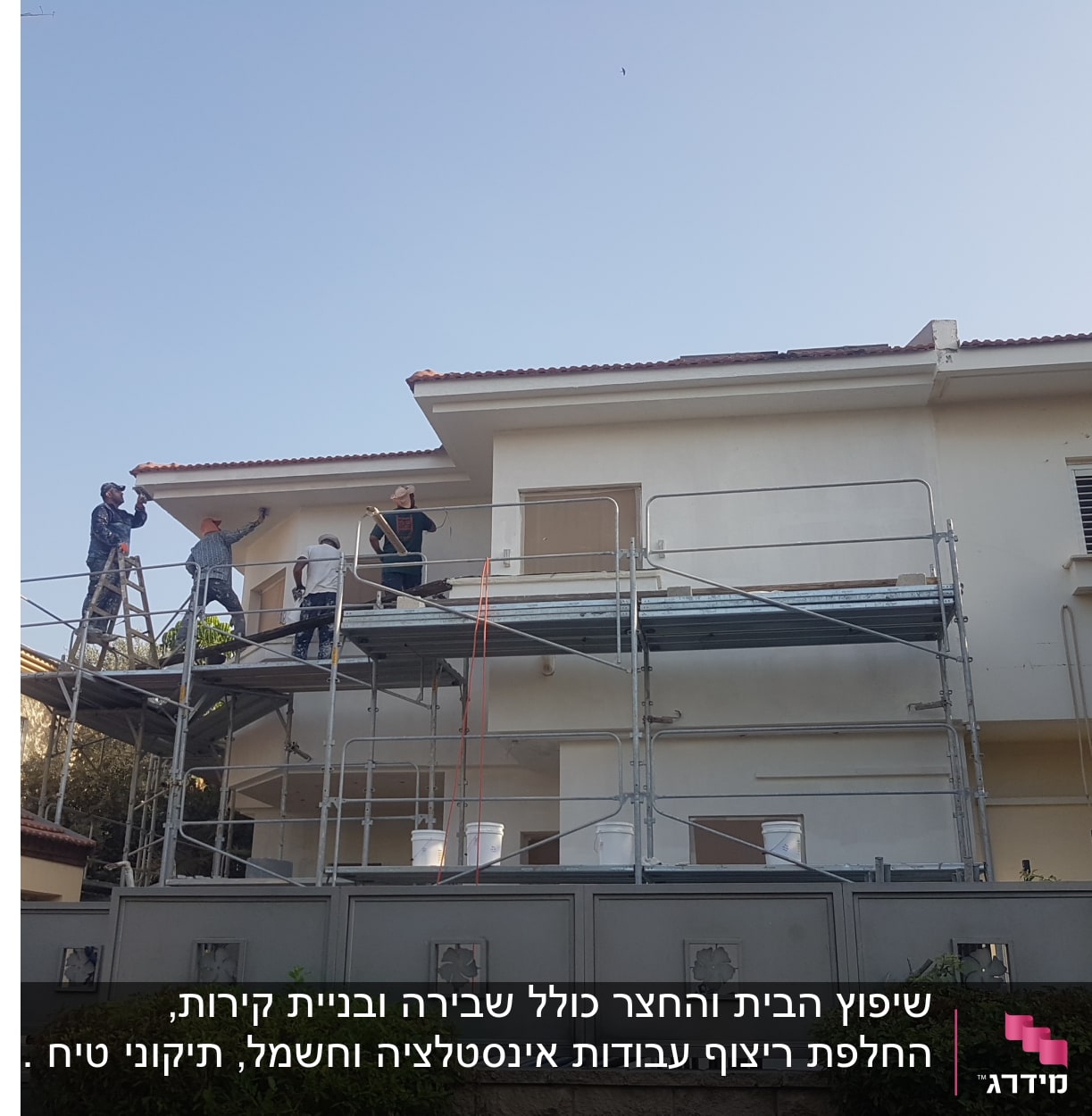 פועלים על פיגומים צובעים קיר חיצוני של בית